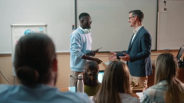 Professor congratulating student with handshake after successful presentation or thesis defense in university classroom. Positive academic achievement and celebration.