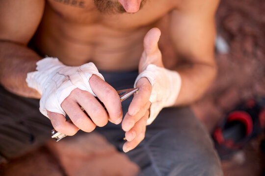 Rock climber removing splinter from injured bandaged hands