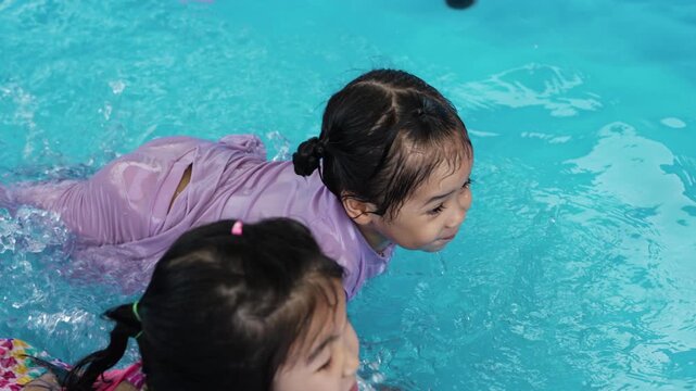 slow motion of happy preschool child girl playing together with her sister in outdoor portable swimming pool in backyard at home