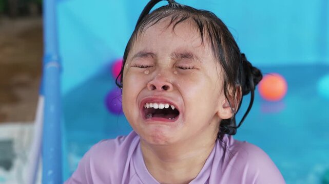 preschool child girl crying and feeling upset while playing in a backyard portable swimming pool