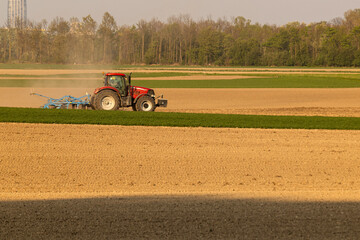 Obraz premium Tractor working on a field in the late afternoon sun near a city