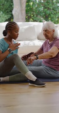 Vertical video: African American coach asking as helping Senior tapping cell to pair watch on mats