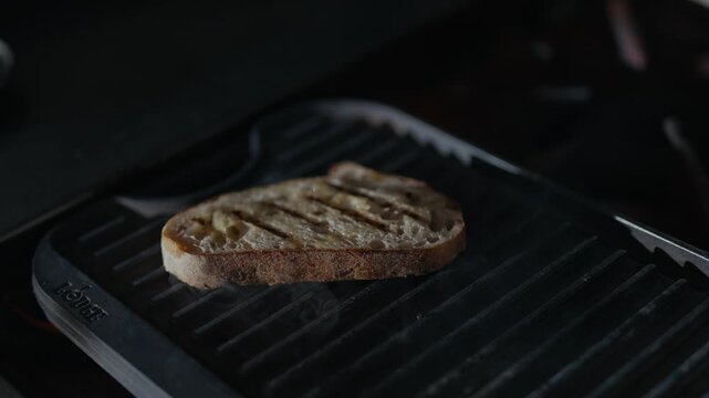 Toasted bread rests on a grill. Grill marks show perfect searing. Dark background emphasizes the food. Simple, appetizing, and inviting. Great for food, cooking, or lifestyle scenes
