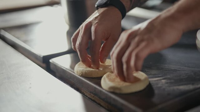 Hands place flat, round items onto a hot surface. Steam rises near a pot in the background. Cooking process shown with slow, deliberate motion. Foods are likely bread or flatbreads
