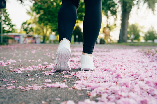 Young woman running through a park surrounded by blooming cherry trees
