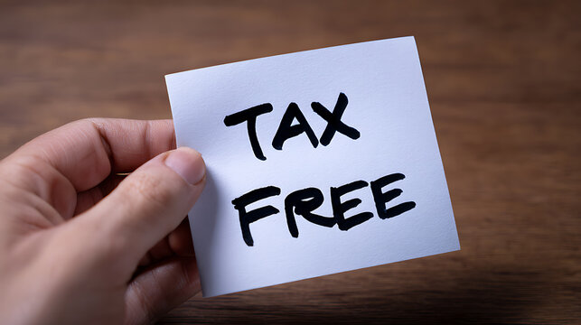 Person holds a white sticky note with 'TAX FREE' written in black marker, suggesting financial benefit, savings, and exemption from charges