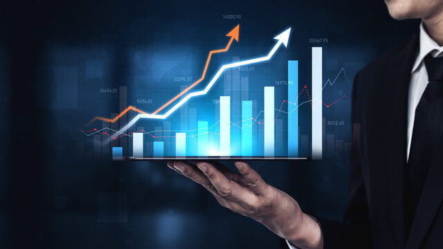A professional businessman stands in an office holding a digital tablet displaying graphs and charts, symbolizing financial growth, market trends, and business success. Scalp
