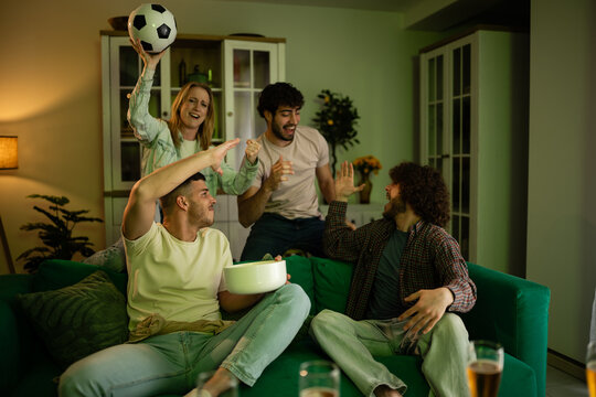 Friends cheering watching football match together at home