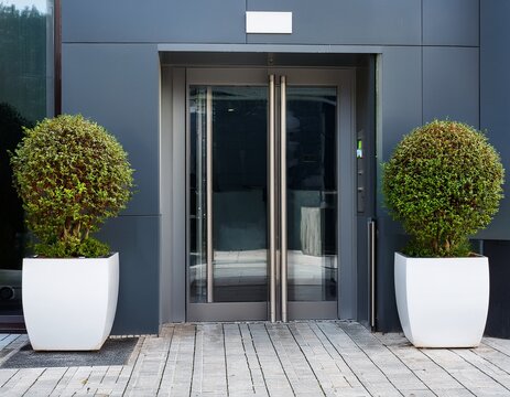 modern building entrance with automatic doors and potted plants in white pots