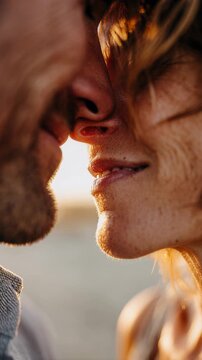 close beach kiss between smiling couple. Intimate close-up of tanned faces nearly touching at golden hour, beads of sand and sunlit stubble visible, eyes