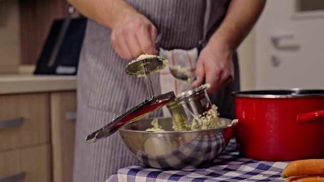 Close-up of a person's hands in a kitchen, using a potato ricer to prepare fresh mashed potatoes for a meal. Healthy, homemade cooking for a delicious dinner.