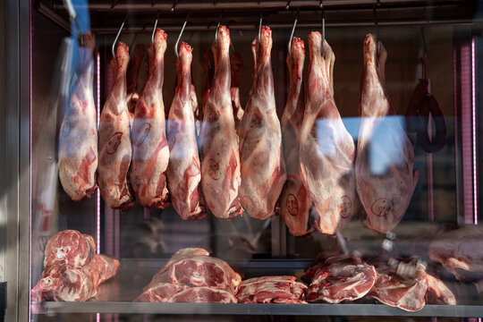 Raw whole carcasses hanging on hooks in butcher market