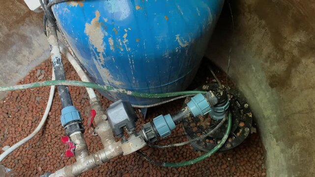 A blue water tank with pipes and valves in a utility area.