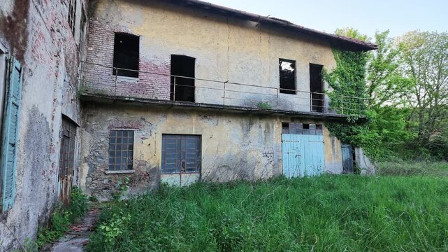Abandoned rural house with weathered facade and overgrown vegetation, old building in countryside showing decay and neglect, moody atmosphere and urban exploration concept.
