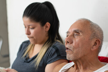 Obraz premium A blind old man listens attentively to his granddaughter during a quiet conversation at home.