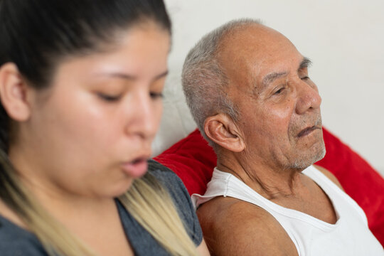 Young caregiver speaking while elderly grandfather listens showing communication and support