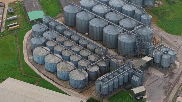 Aerial view of large metal grain storage silos and industrial facility with water treatment plant infrastructure in Hemswell Cliff, England, United Kingdom.