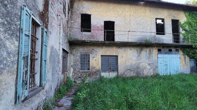 Abandoned rural house with weathered facade and overgrown vegetation, old building in countryside showing decay and neglect, moody atmosphere and urban exploration concept.
