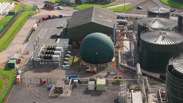 Aerial view of grain storage silos and water treatment plant with industrial tanks and a green biogas dome in Hemswell Cliff, England, United Kingdom.