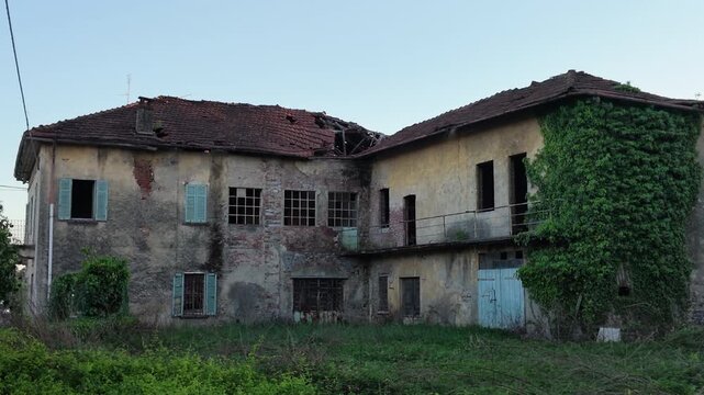Abandoned rural house with weathered facade and overgrown vegetation, old building in countryside showing decay and neglect, moody atmosphere and urban exploration concept.
