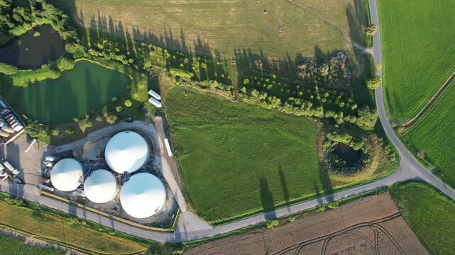 Aerial view of agricultural complex of barns and biogas production domes and storage tanks, bio renewable energy generation from rural panorama landscape Europe