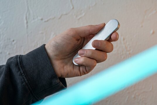 Close-up of a hand holding a brushed aluminum haptic controller. The minimalist design and metallic texture represent the peak of industrial design and tactile luxury in 2026.