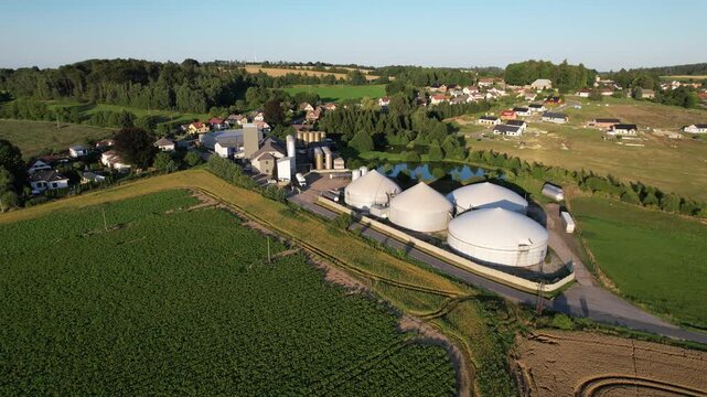 Aerial view of agricultural complex of barns and biogas production domes and storage tanks, bio renewable energy generation from rural panorama landscape Europe