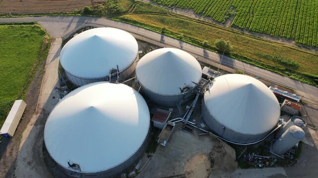 Aerial view of agricultural complex of barns and biogas production domes and storage tanks, bio renewable energy generation from rural panorama landscape Europe