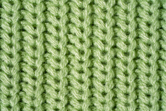Close-up sweater texture in pastel green color, macro knitted surface and synthetic fiber detail. Concept tactile textile material, durable easy-care knitwear, conscious longer-lasting clothing choice