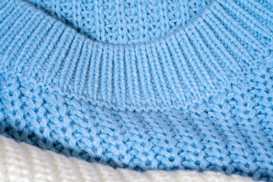 Close-up of pastel blue color sweater neckline with ribbed collar and knitted texture in synthetic material. Macro knitwear detail with soft tactile surface. Concept of casual cold season clothing