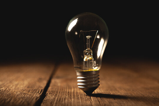 Incandescent light bulb on a wooden background. Energy saving concept.