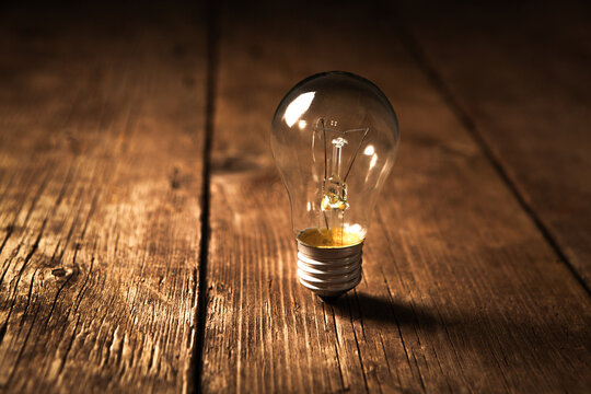 Incandescent light bulb on a wooden background. Energy saving concept.