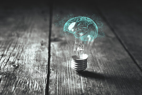 Idea concept with glowing light bulb and human brain on wooden table