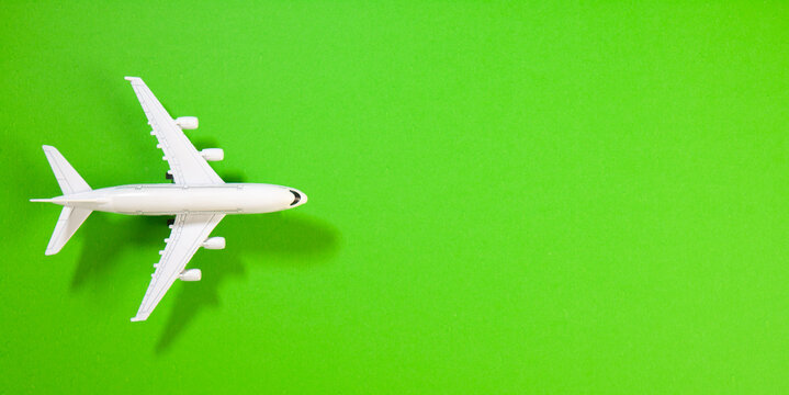 Miniature model airplane on green background with copy space. Travel concept