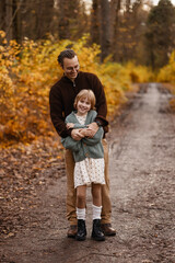 Fototapeta premium Father Hugging Daughter In Warm Embrace On Muddy Trail With Smiling Faces And Cozy Layers, Intimate Protective Moment Surrounded By Autumn Foliage And Soft Light Conveying Safety And Deep