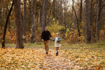 Fototapeta premium Father And Daughter Running Side By Side Down Leafy Path, Carefree Laughter And Energetic Stride With Windtossed Hair And Playful Momentum Among Amber Foliage Capturing Spontaneous Family