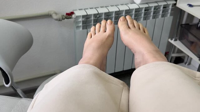 Close-up of a woman seated in a pedicure chair during a salon treatment. The technician adjusts the chair position to raise and lower the leg support for optimal comfort and proper procedure setup.