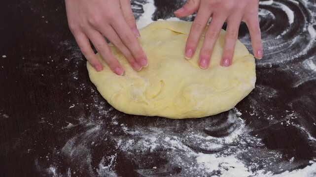 Woman hands stretching dough on floured wooden table pizza dough preparation closeup baking