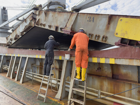 deck crew of ship paint hatch coaming of cargo hold. routine seafarer job and life
