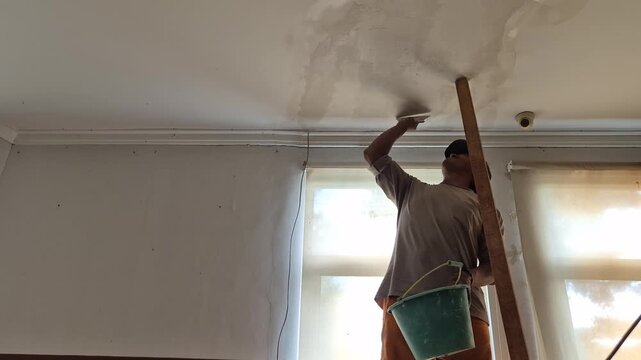Construction worker is repairing a ceiling.