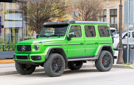 Vibrant neon green Mercedes-Benz G-Class luxury SUV parked on an urban street. The rugged vehicle stands out with its bold color, modern design, and high ground clearance