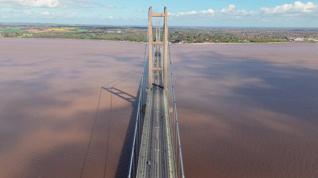 Aerial view of the Humber Bridge suspension bridge spanning the silty waters of the Humber Estuary under a blue sky Hessle, East Riding of Yorkshire, United Kingdom.