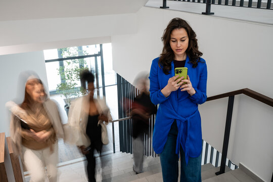 Woman scrolling smartphone distraction walking office stairs
