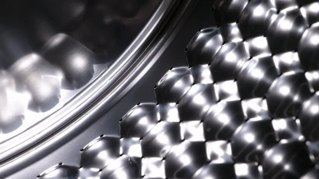 Stainless steel washing machine drum rotating. Empty washing machine drum with a unique honeycomb pattern made of shiny stainless steel spinning, highlighting modern laundry appliance technology