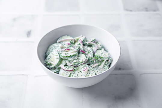 Cucumber red onion dill salad in a bowl on a white background