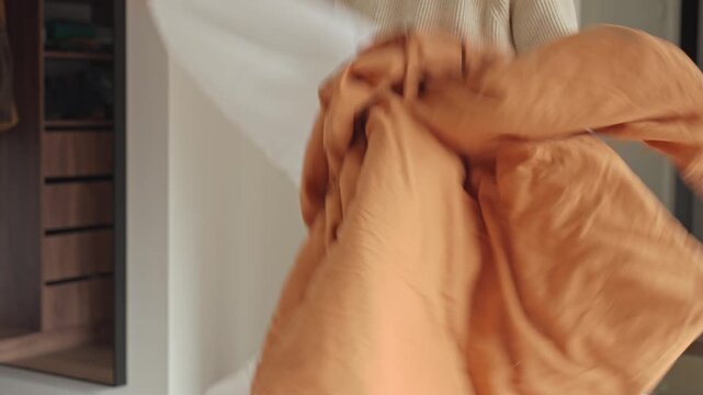 Woman pulls white blanket out of duvet cover indoors. Bedding, laundry and housekeeping