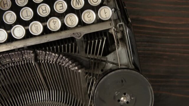 Woman fingers typing on retro vintage typewriter on wooden desk close up top view