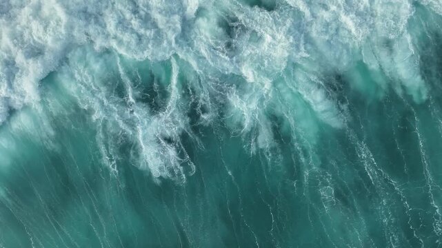 Aerial view of powerful turquoise ocean waves crashing with white foam and spray in the Indian Ocean, Bali, Indonesia.
