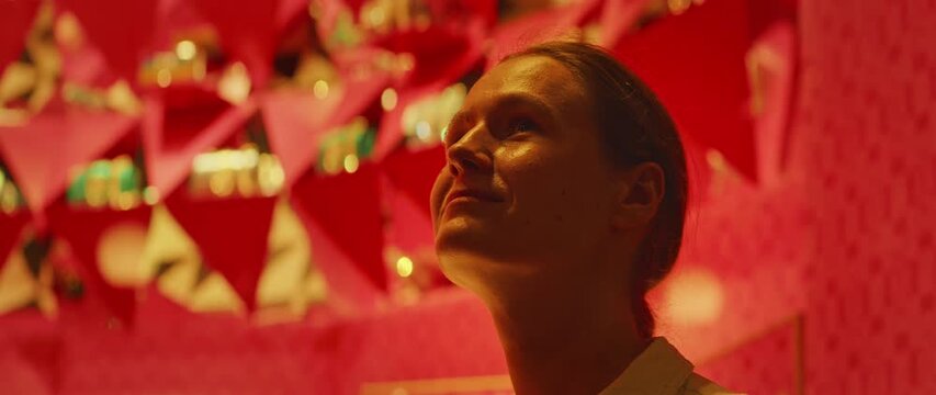 Woman gazing upward in a shop with a vibrant red interior mesmerized by the luxury items inside