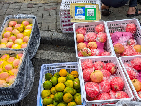 Hunan, China, Sep. 22, 2024. Street view of a China local fruit stall with WeChat Pay and Alipay QR code signs for mobile payments placed behind the fruits.